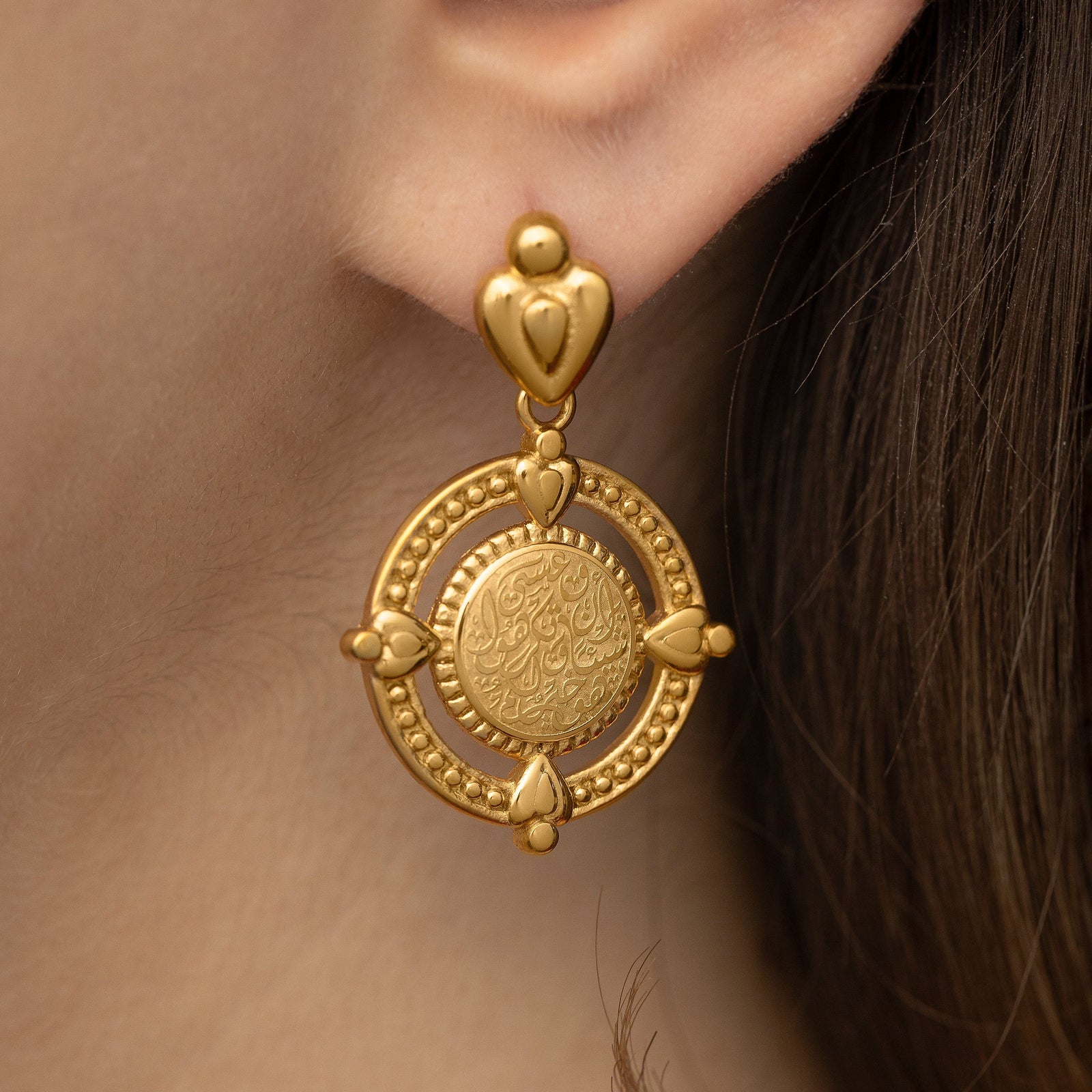 Close up of the gold earring worn by the model.