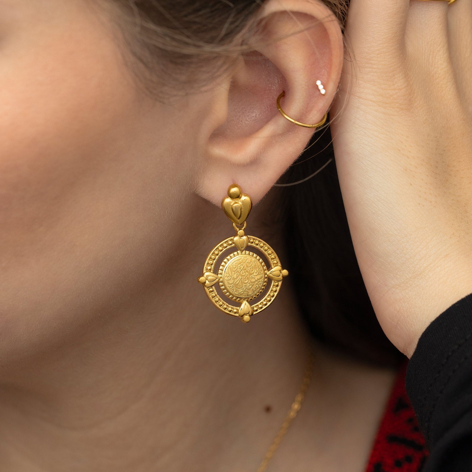 Close up of the gold earring worn by the model.