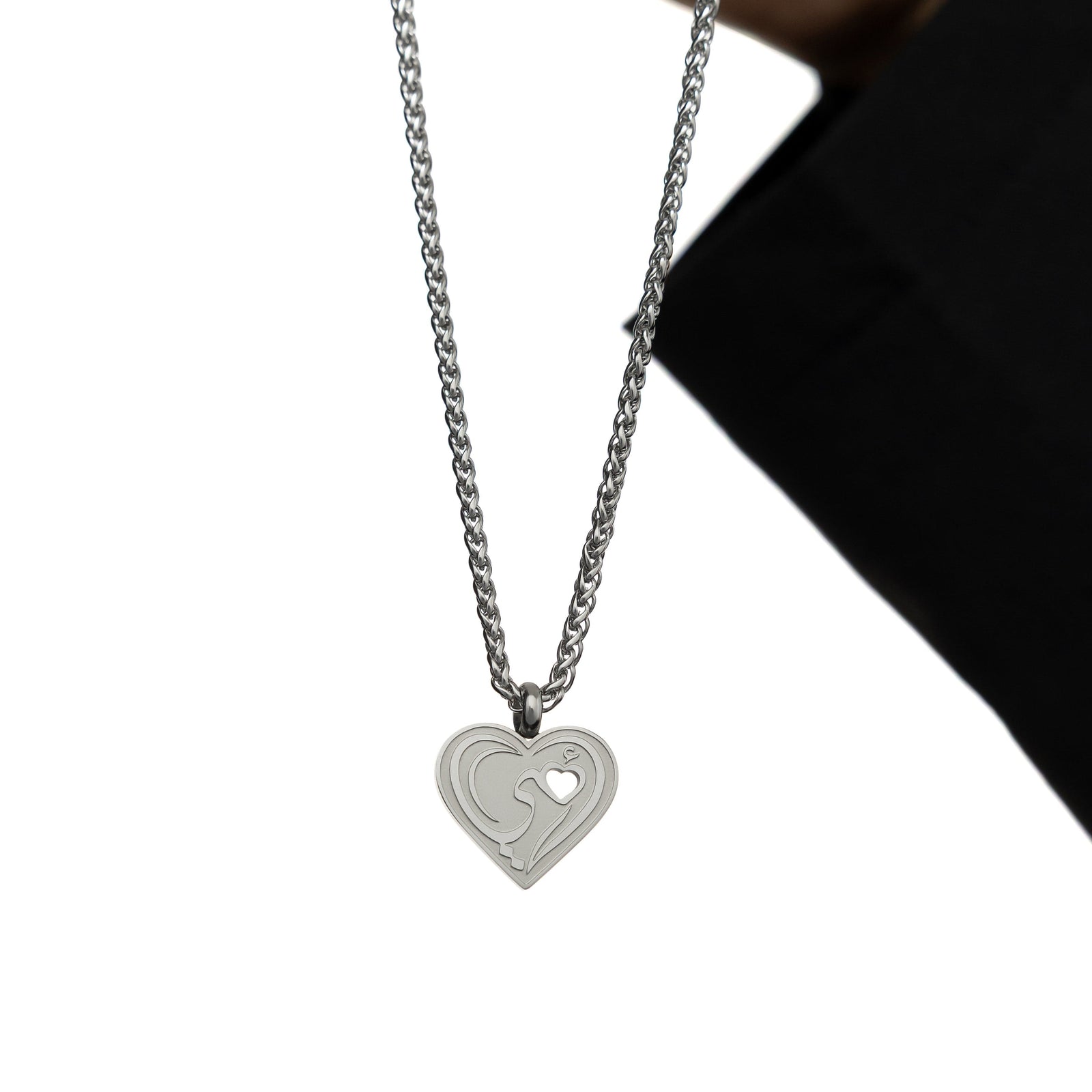 Photo of the silver "Piece of Me" Mama Necklace as held by the model against a white background.