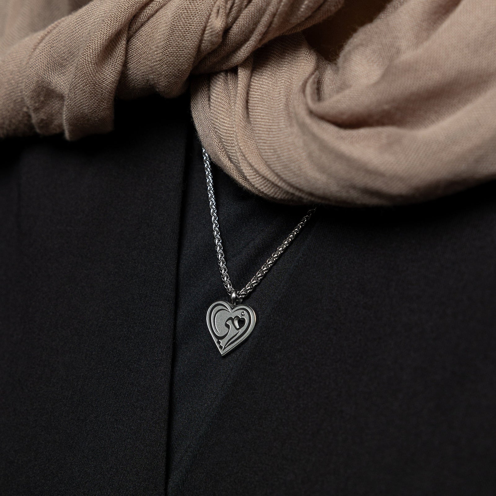 Close up of the silver "Piece of Me" Mama Necklace as worn by the model