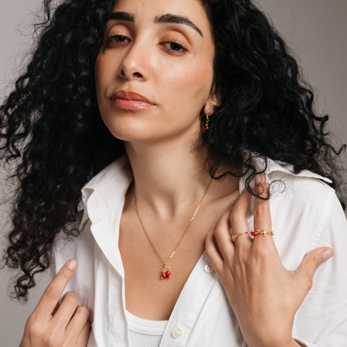 Model styled in 18k gold-plated Nominal jewelry featuring the Pomegranate Necklace, Pomegranate Vine Ring, and Rose Ring.