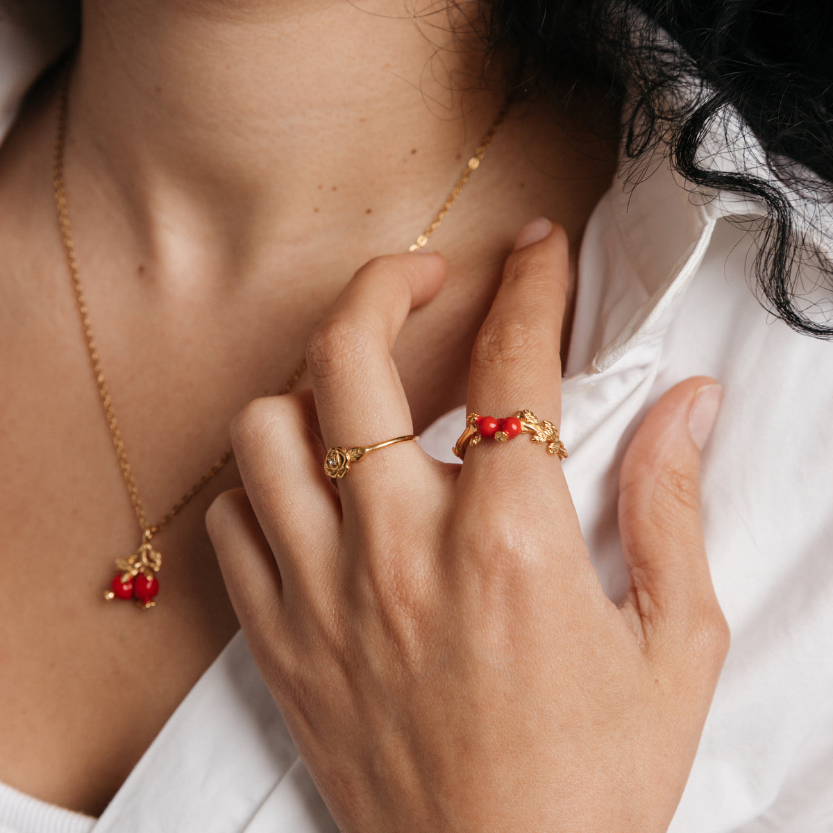 Model styled in 18k gold-plated Nominal jewelry featuring the Pomegranate Vine Ring, Rose Ring, and Pomegranate Necklace.