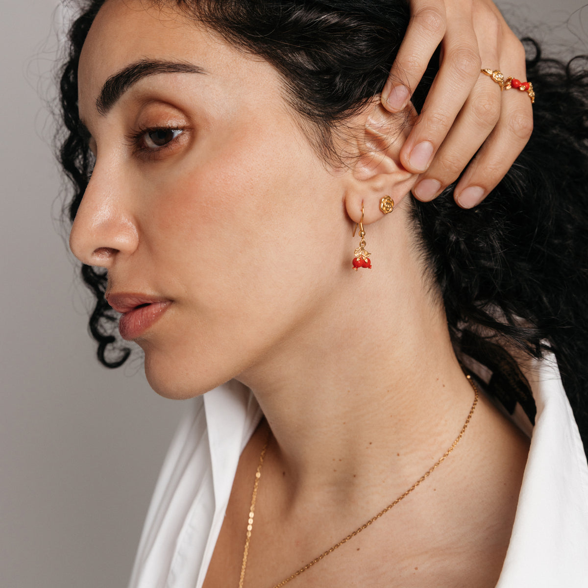 Model styled in 18k gold-plated Nominal jewelry featuring the Pomegranate Vine Earrings, Rose Studs, and Pomegranate Vine Ring.