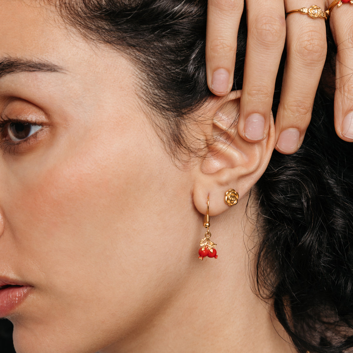 Model styled in 18k gold-plated Nominal jewelry featuring the Pomegranate Vine Earrings, Rose Studs, and Pomegranate Vine Ring.