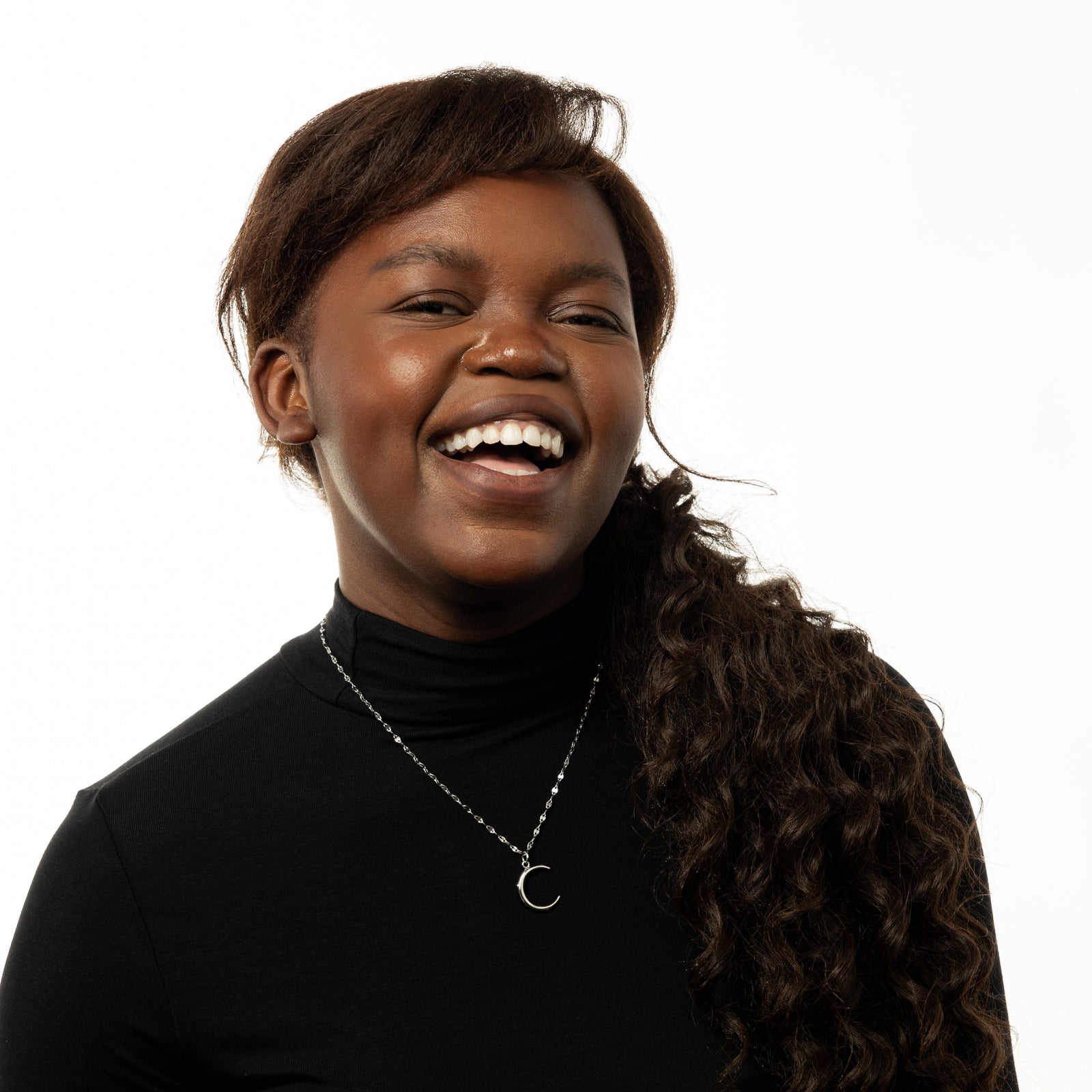 Photo of the model smiling to the camera. The model is wearing the silver Premium Crescent Necklace.