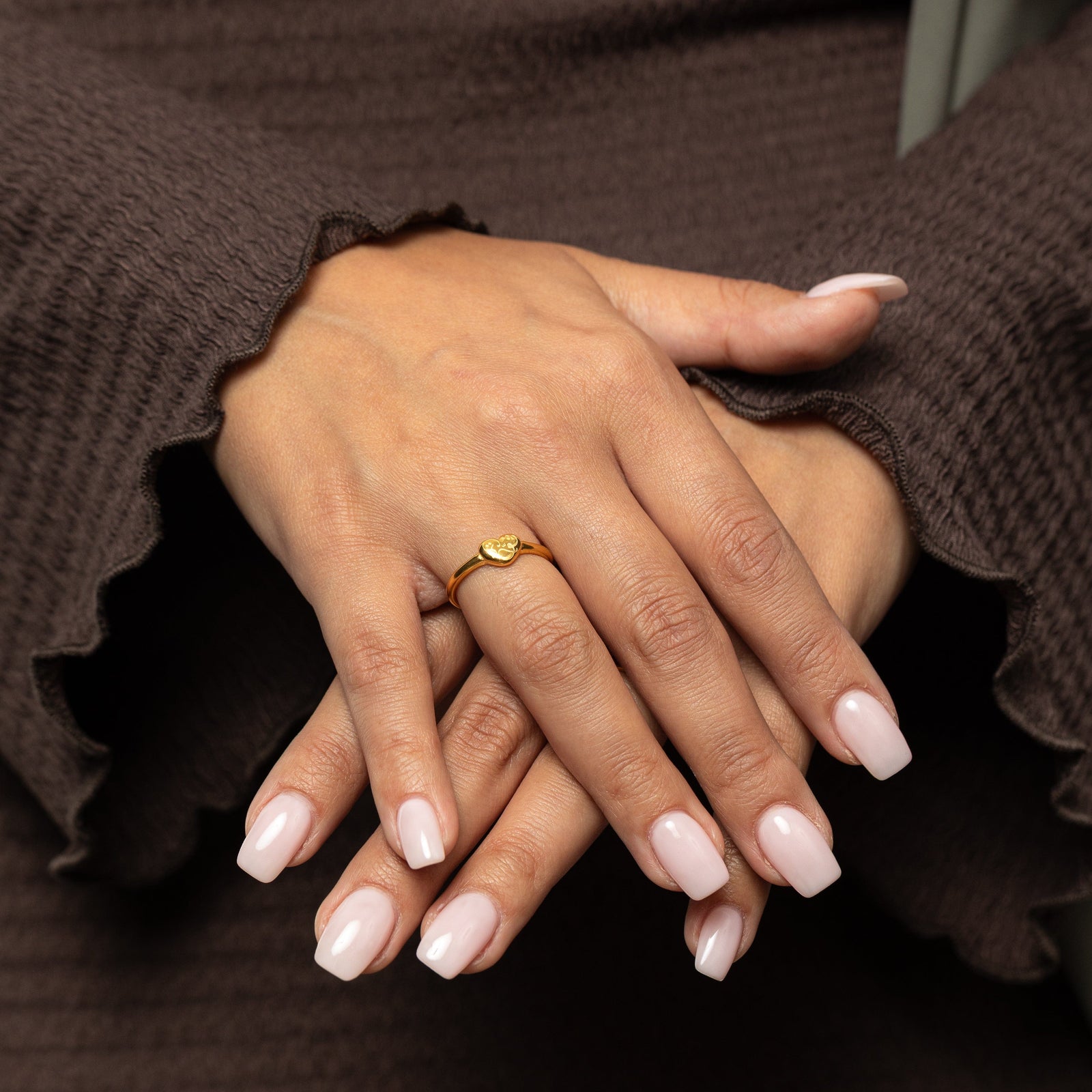 Close-up of a hand wearing a gold Quwa | Strength Heart ring