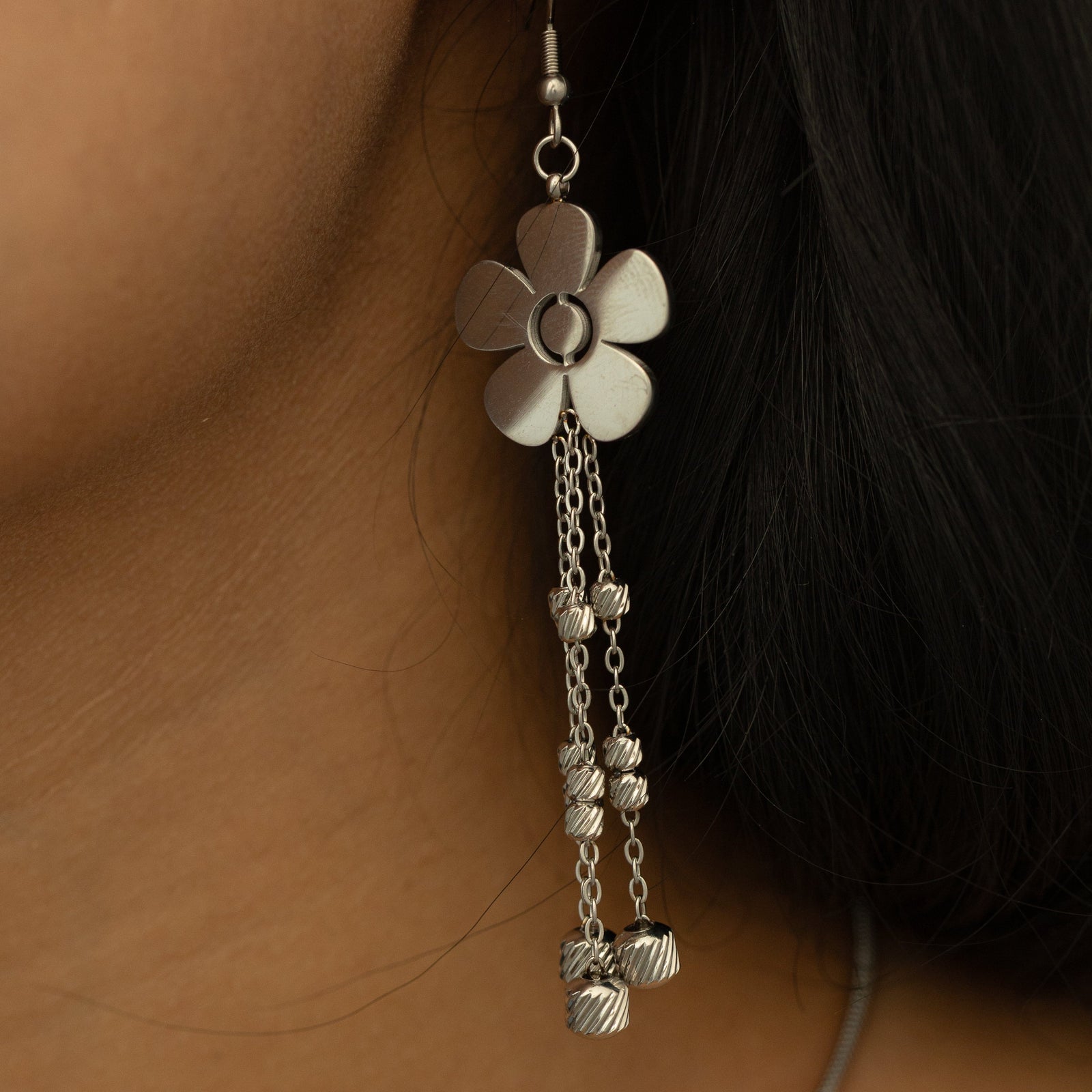 Close-up of a single silver Raining Flower Earring worn on the ear, showing the dangling beaded chains swaying below the flower.