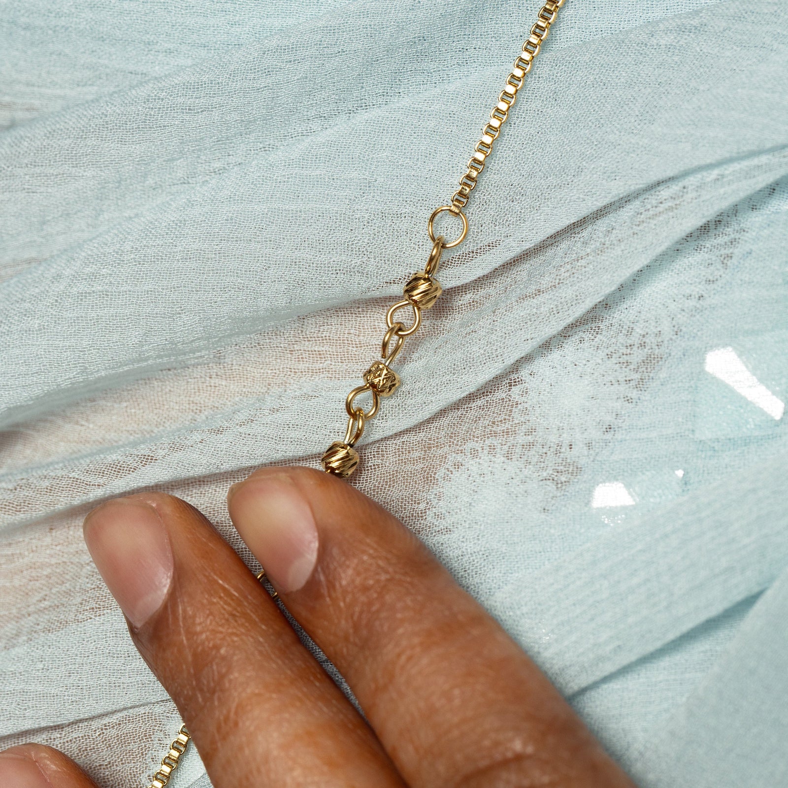 Close up of the thin gold chain of the Raining Paisley Necklace.