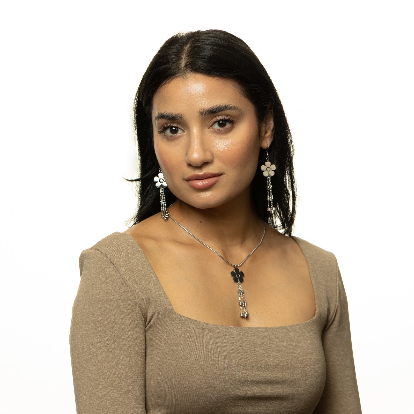 Woman wearing the silver Raining Flower Necklace and matching earrings, styled with a beige square-neck top.