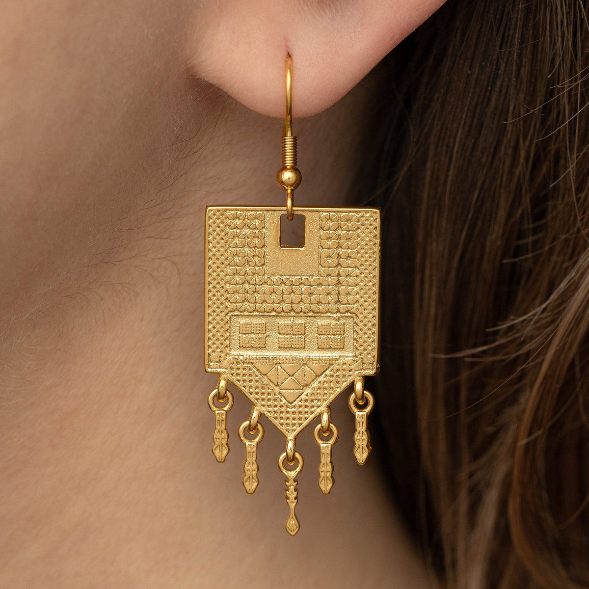 Close up photo of the gold Raining Tatreez Earrings as worn by the model.