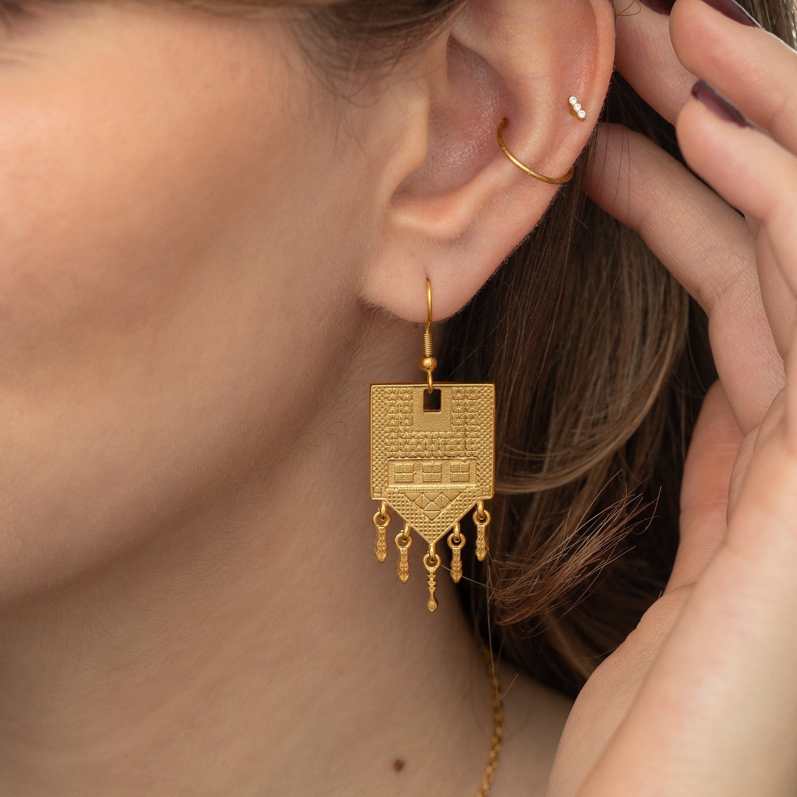 Close up photo of the gold Raining Tatreez Earrings as worn by the model.