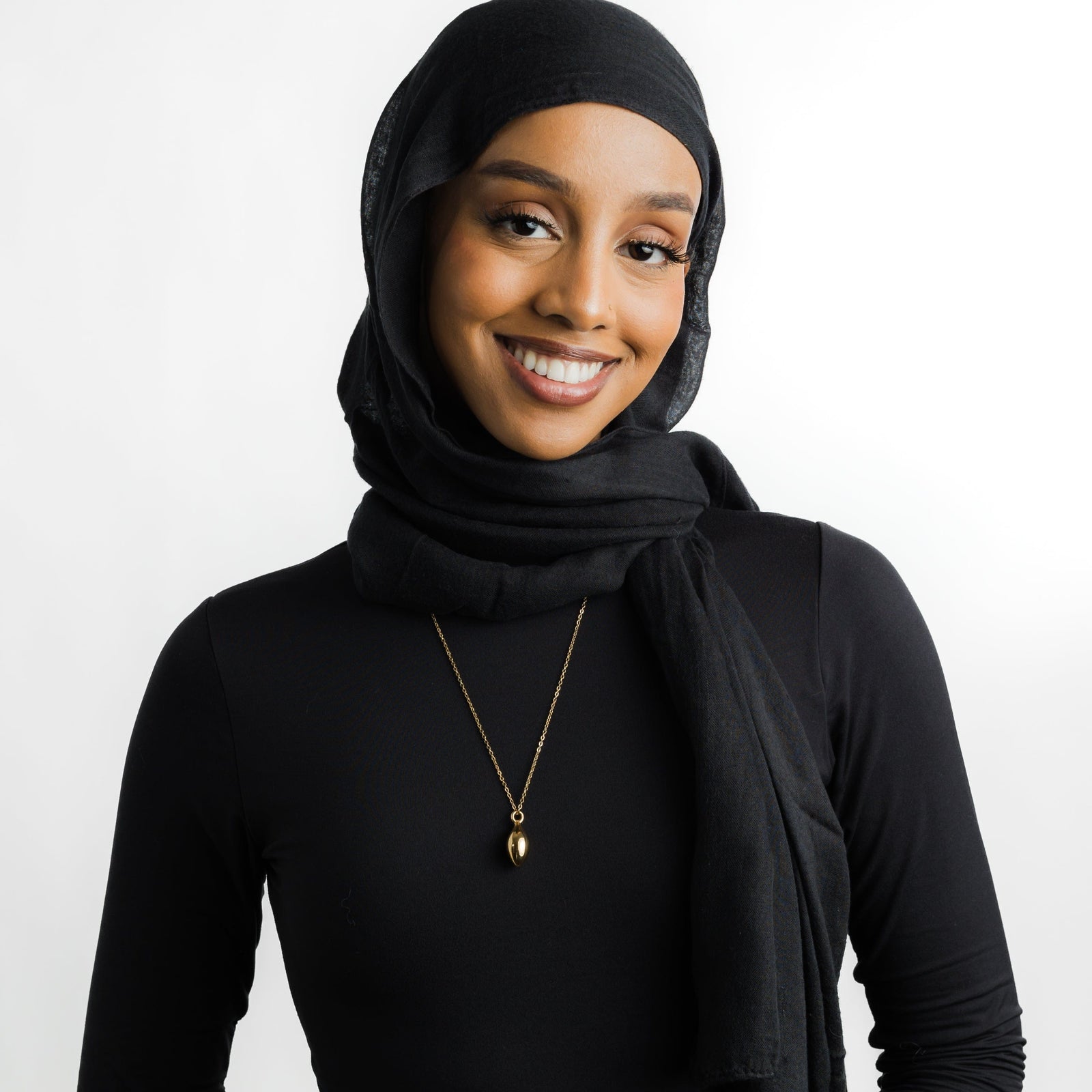 Photo of the model wearing the gold Palestinian Olive Necklace.