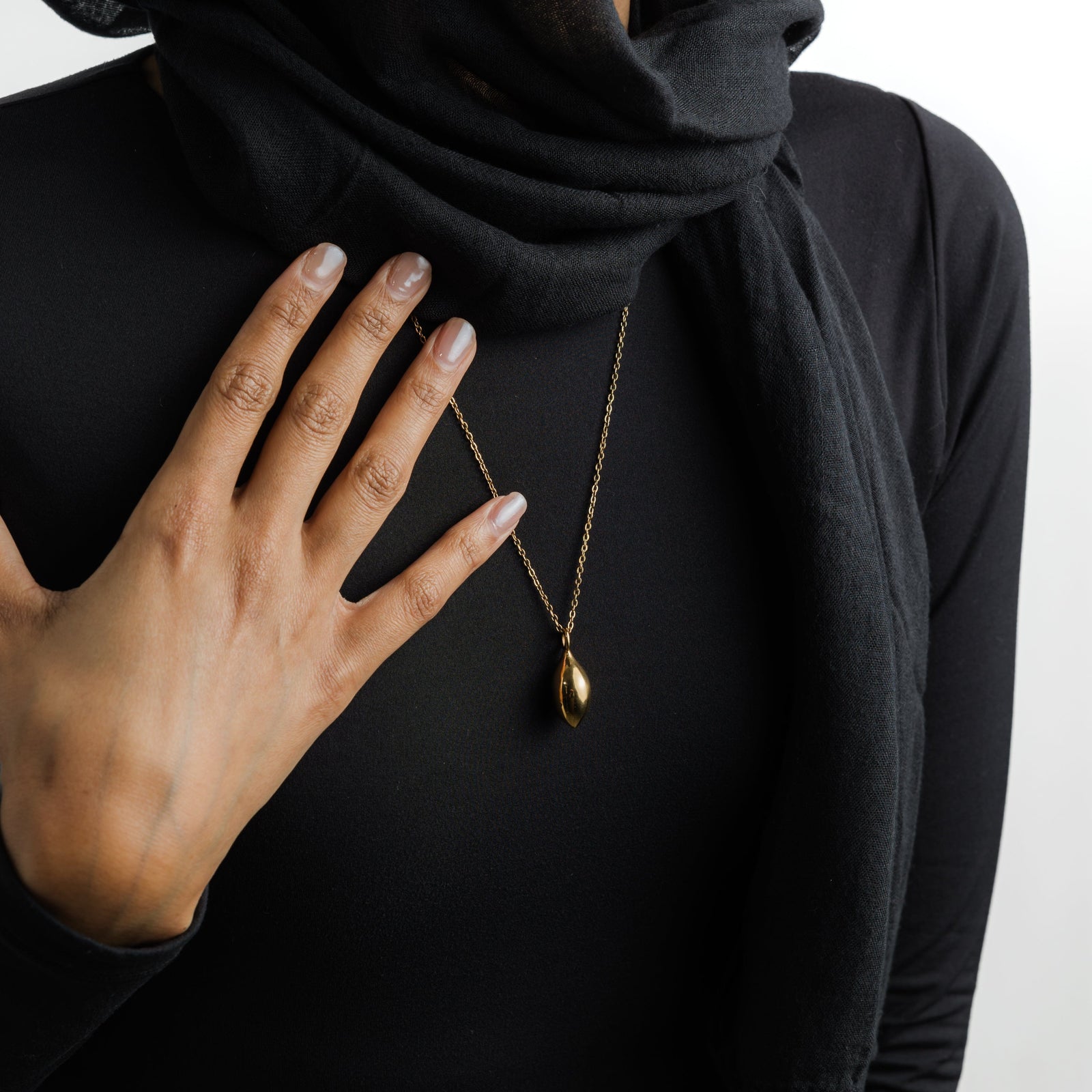 Close up of the gold Palestinian Olive Necklace as worn by the model.