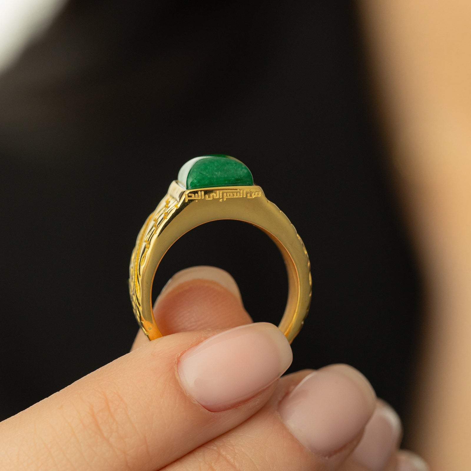 Close up of the model holding the ring to show the engraving, "From the river to the sea" in Arabic Calligraphy.