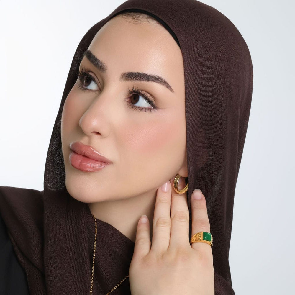Photo of the model looking away from the camera and touching the side of their neck with their left hand. The model is wearing the "River to Sea" Onyx Ring | Women on their left index finger.
