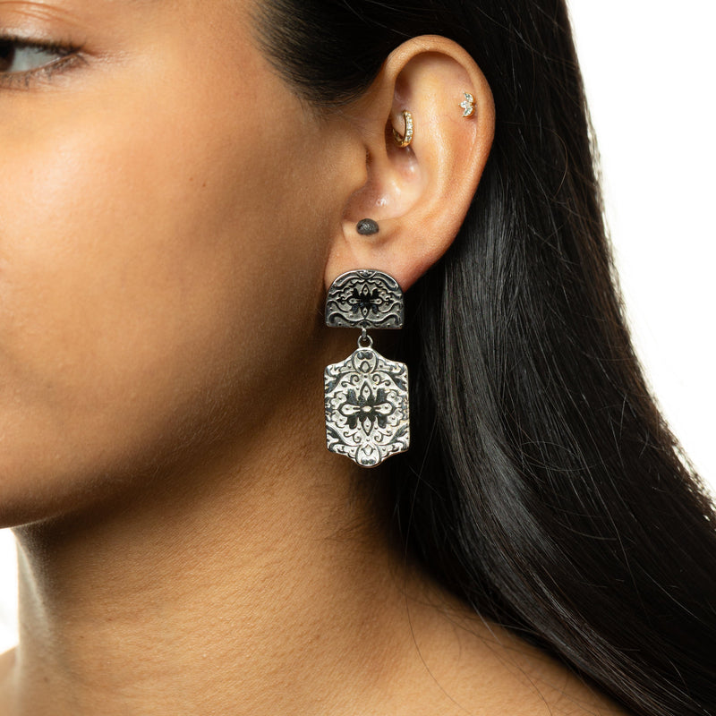 Silver Roaming Earring with intricate engraved floral design hanging from ear.