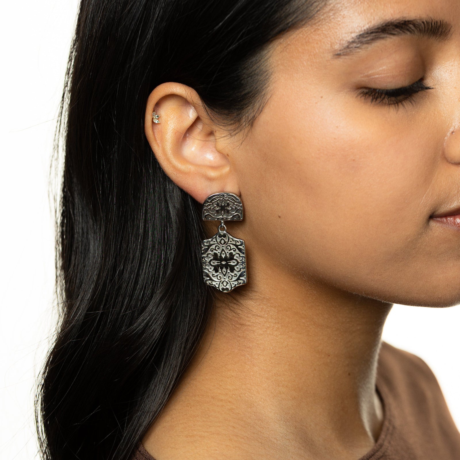 Silver Roaming Earring featuring detailed floral and vine engravings, dangling from ear.