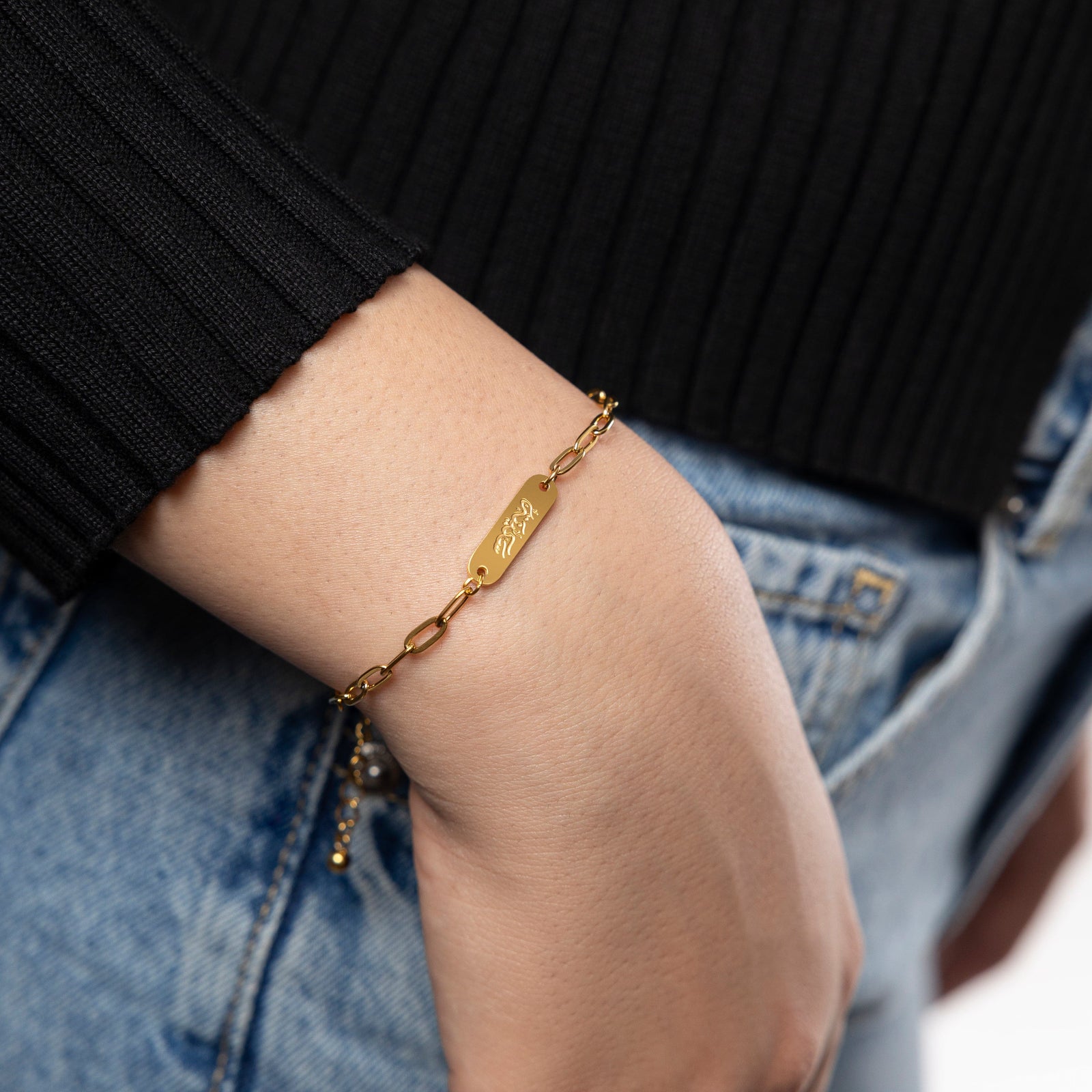 Woman wearing gold Sakinah Serenity bracelet, showing the arabic engraving.
