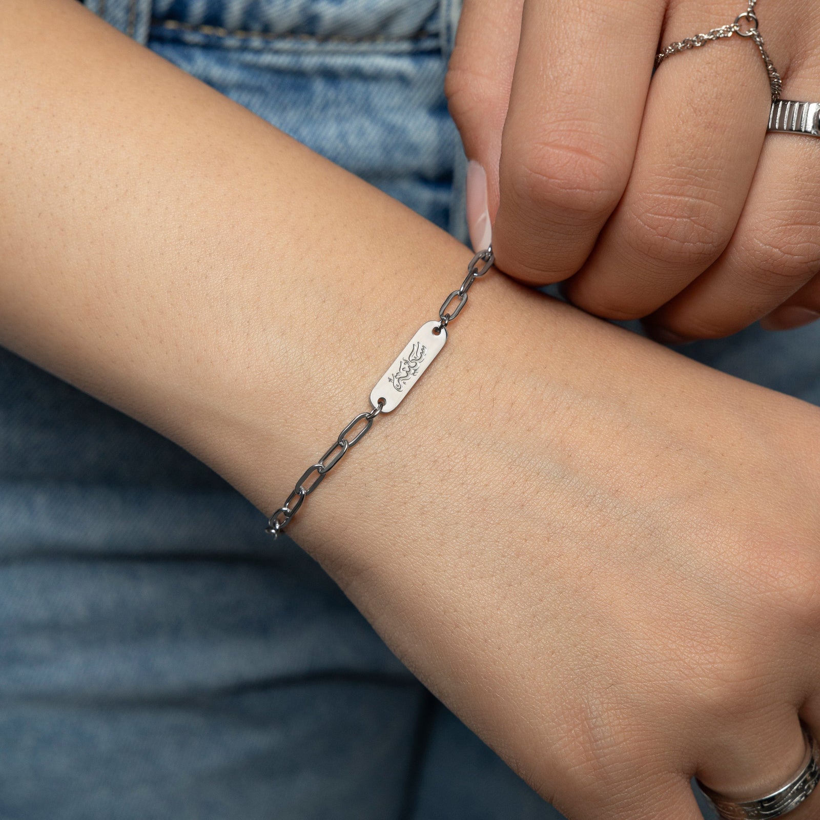 Woman wearing silver Sakinah Serenity bracelet, showing the arabic engraving. 