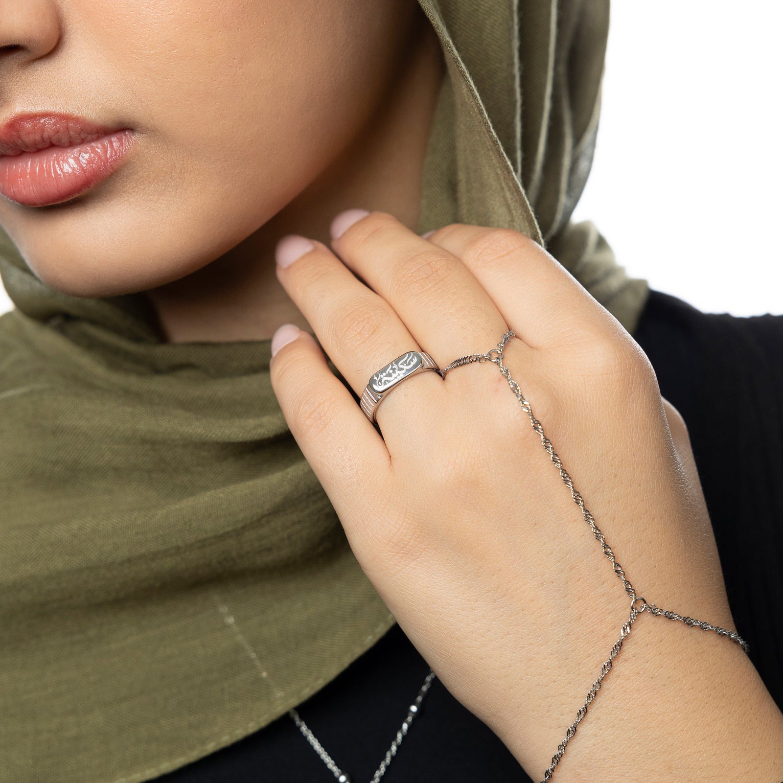 Silver Sakinah serenity ring and silver twisted hand chain worn with a muted olive hijab and black top.