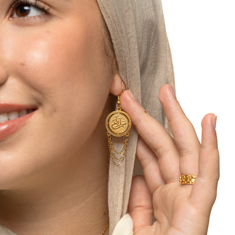 Gold Salam Vintage Token Earring with a round calligraphy disc and hanging chains worn on a woman’s ear.