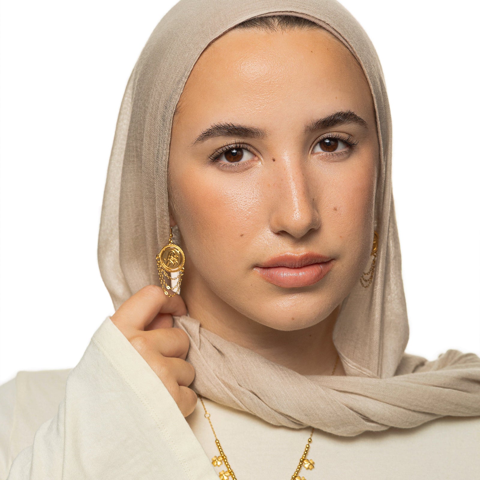 Woman wearing the gold Salam Vintage Token Earrings with round calligraphy discs and layered chain tassels.