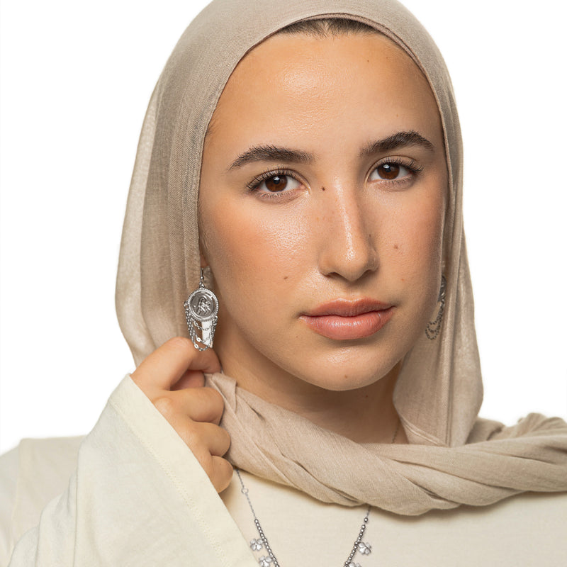 Woman wearing the silver Salam Vintage Token Earrings with round calligraphy discs and layered chain tassels.