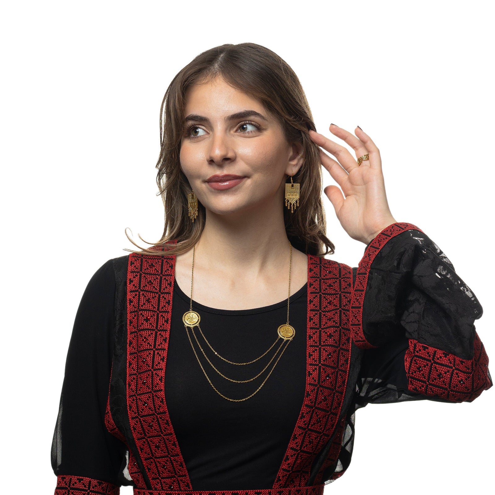 The model is wearing the gold Salam | Peace Layered Token Necklace, a pair of gold dangling earrings, and a gold ring on their left ring finger.