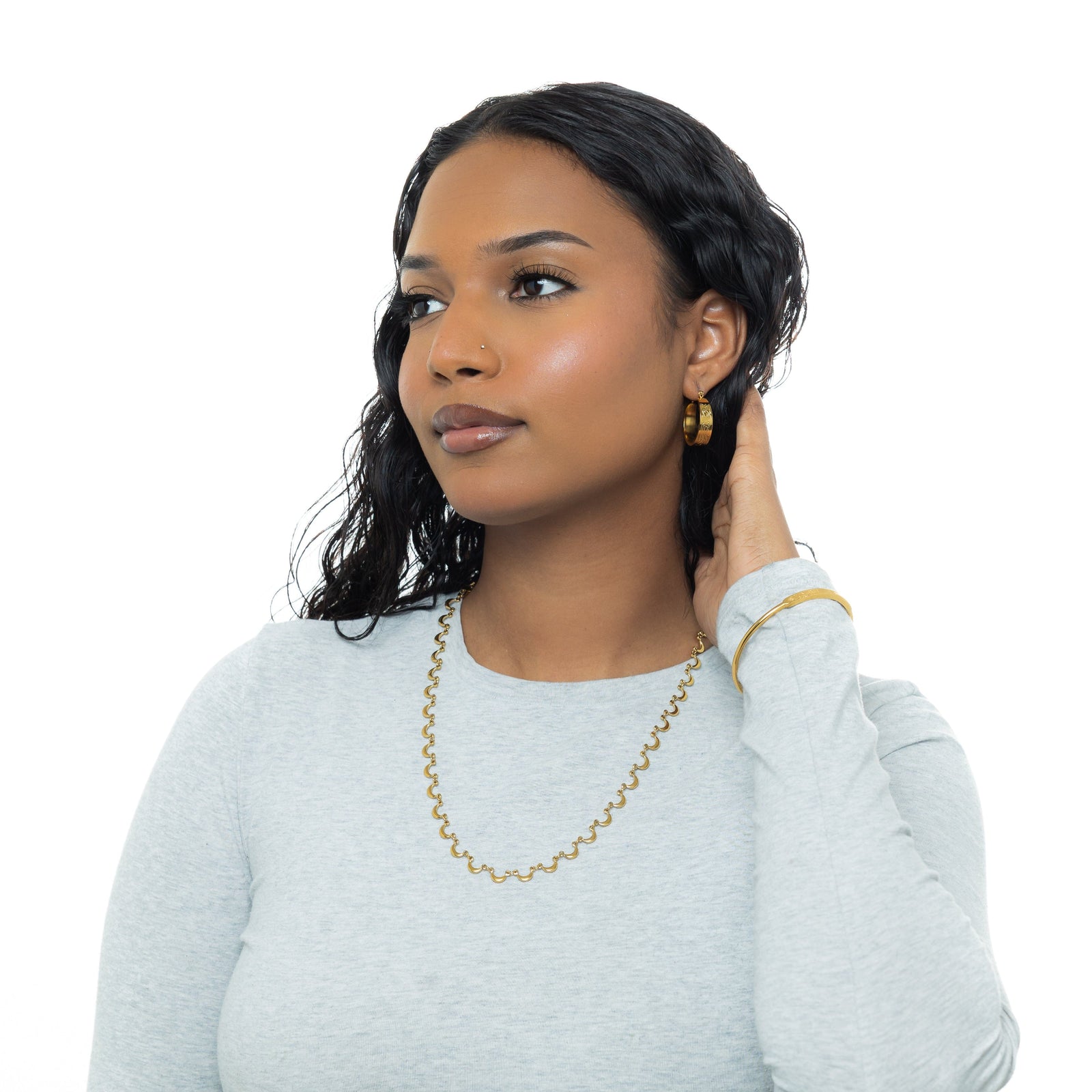 A model wearing the 18K gold-plated Skyfall Necklace. The crescent charms rest delicately along her collarbone, complementing her minimalist attire.