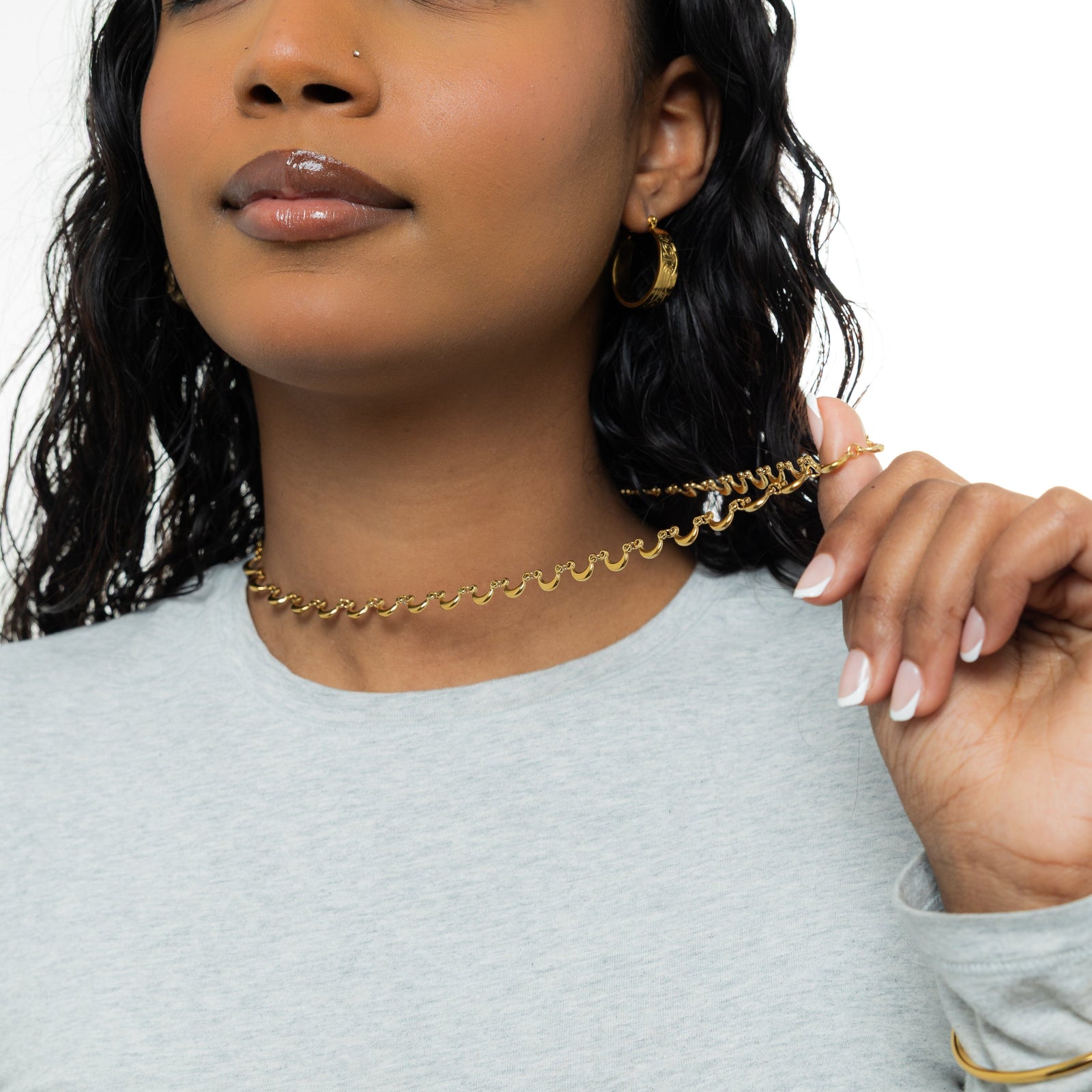 A model wearing the 18K gold-plated Skyfall Necklace. The crescent charms rest delicately along her collarbone, complementing her minimalist attire.