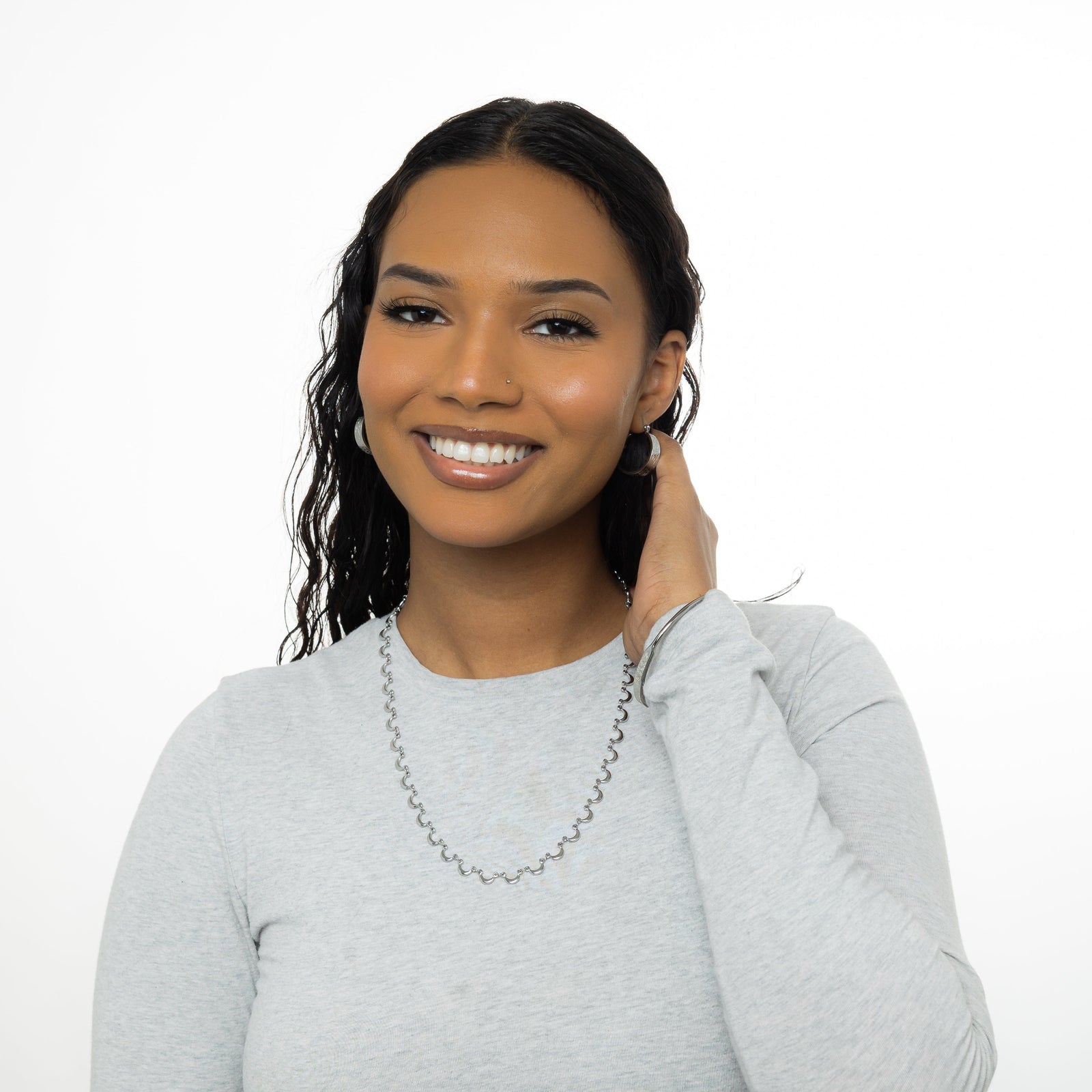 A model showcasing the silver Skyfall Necklace. The crescent-shaped charms lay gracefully on her neckline, highlighting the necklace's celestial design.