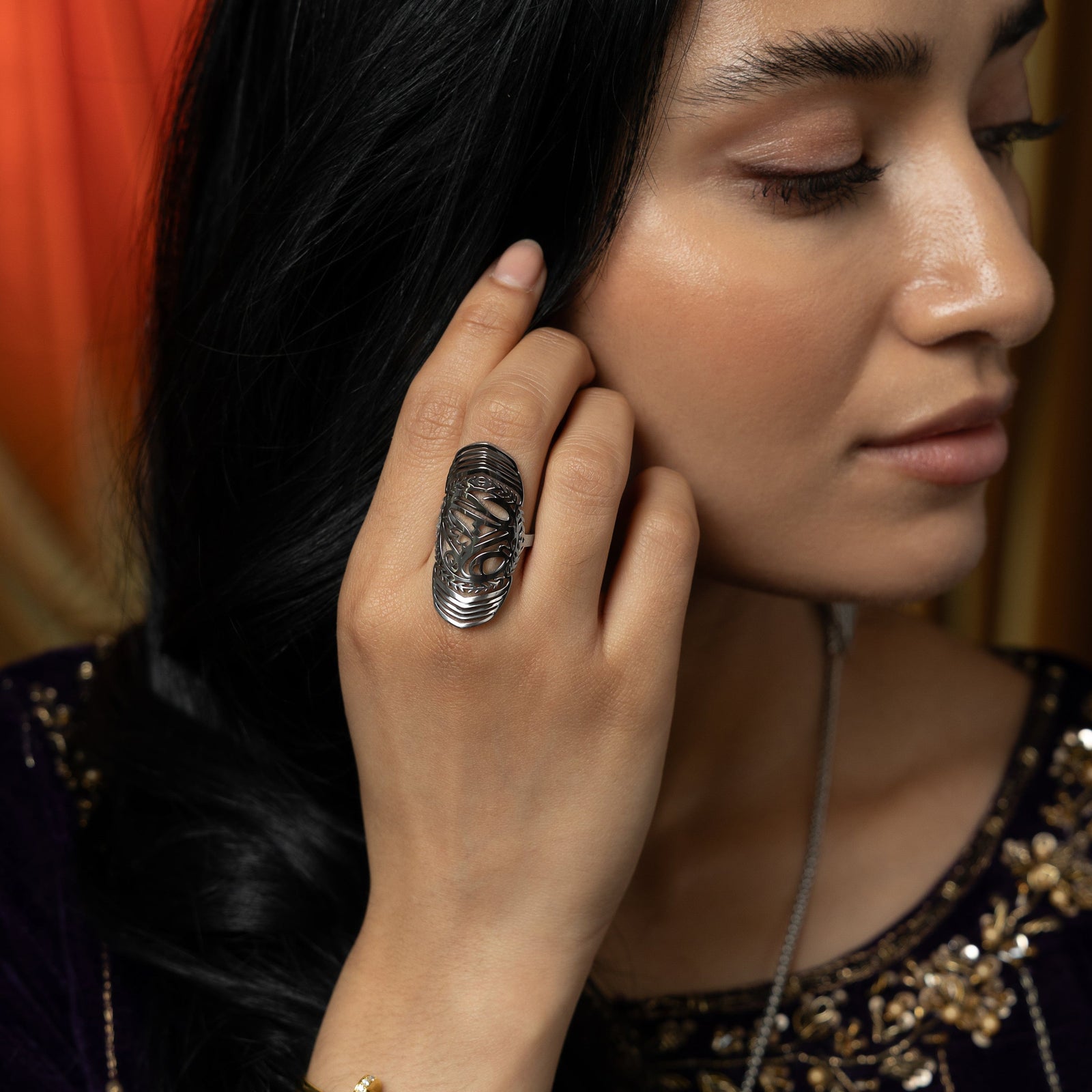 Woman wearing the silver sufficient  ring on her finger, styled with a deep purple outfit.