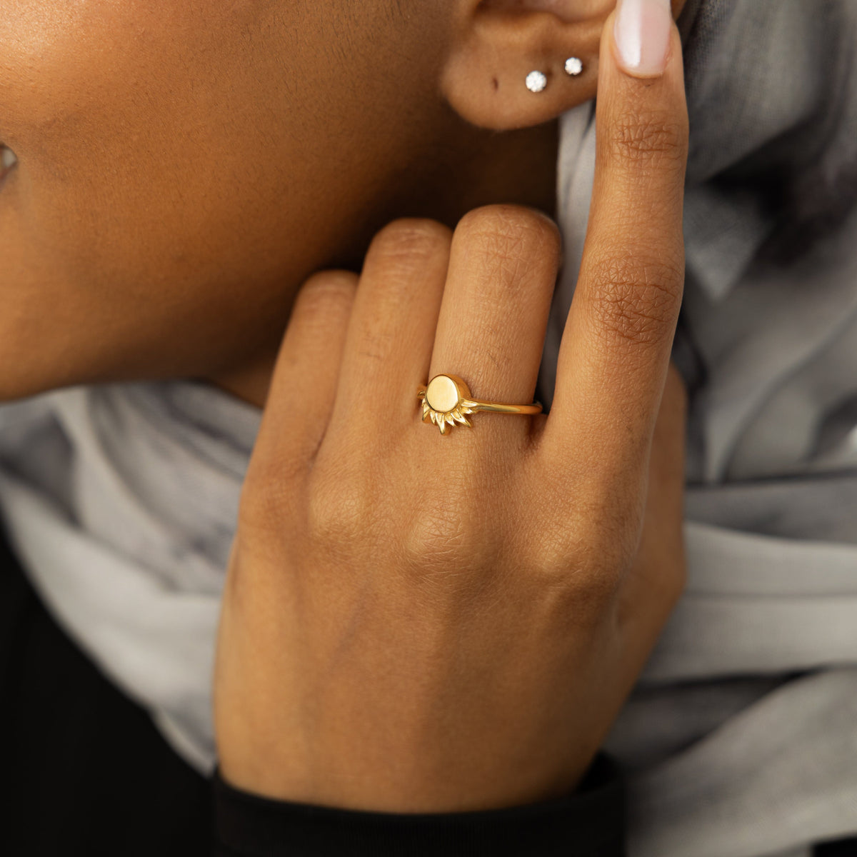Hand wearing a gold sun ring