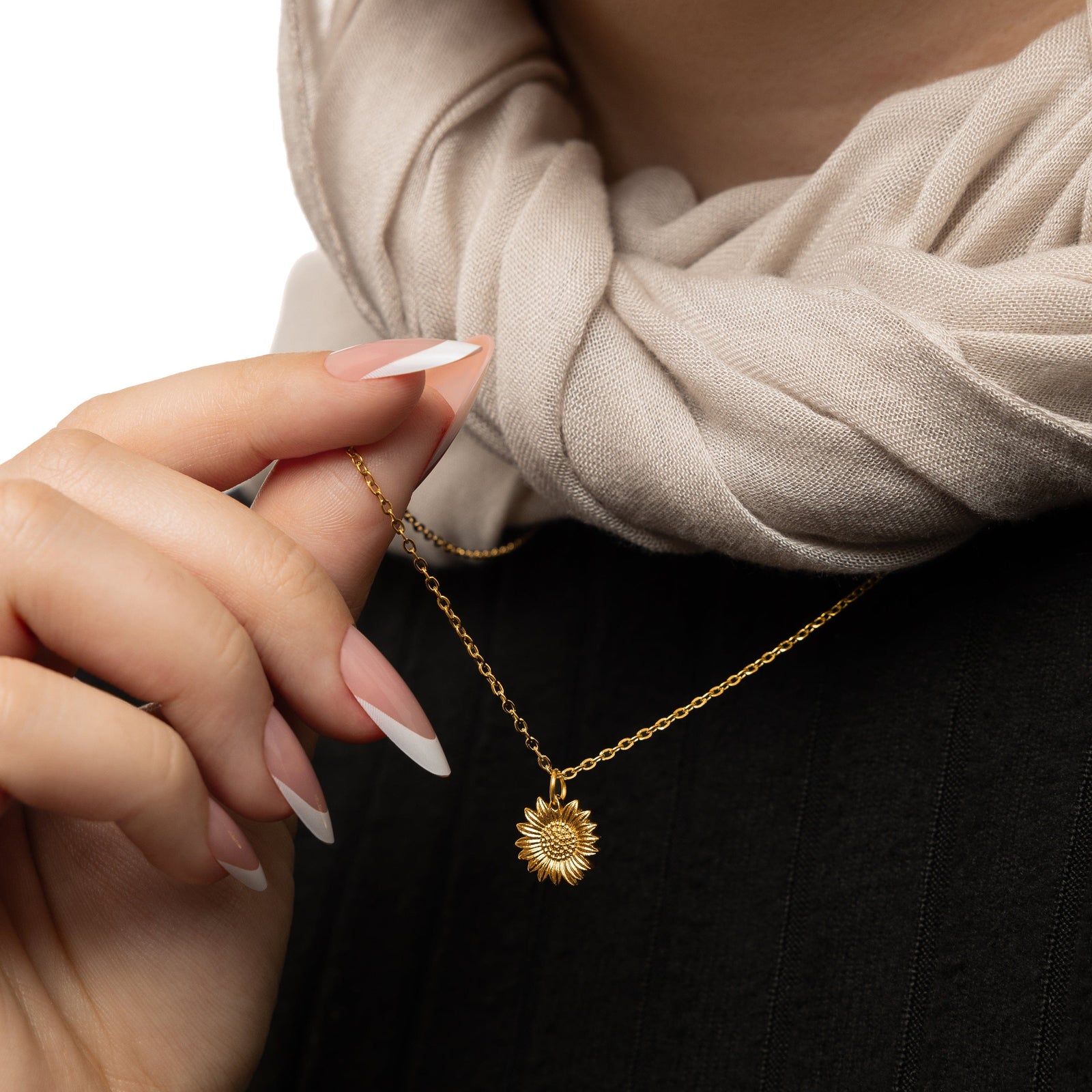 Model gently holds the gold chain to show the hanging pendant of the gold Sunflower Necklace.