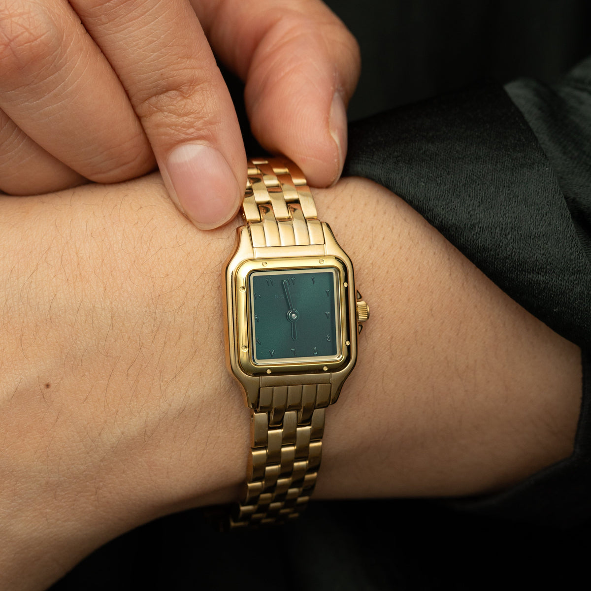 Model touching the gold watch on their wrist.