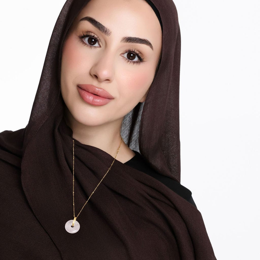 Photo of the model looking and smiling to the camera. The model is wearing the "Surely in the remembrance of Allah, hearts find comfort" Pink Quartz Stone Necklace