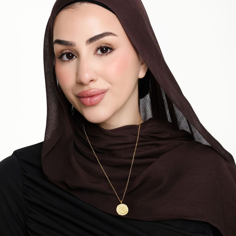 Photo of the model smiling to the camera. The model is wearing the gold Tatreez Necklace | Women.
