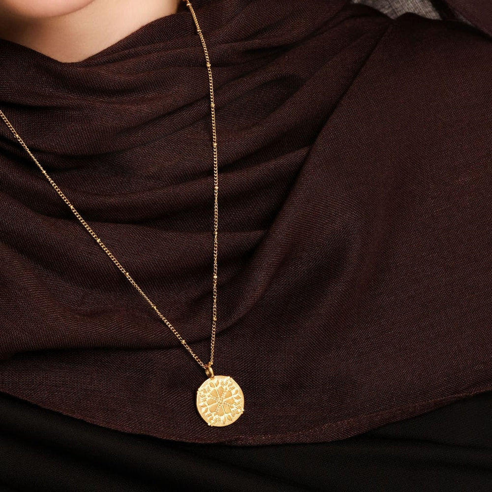 Close up of the gold Tatreez Necklace | Women against the brown fabric of the model's clothing.