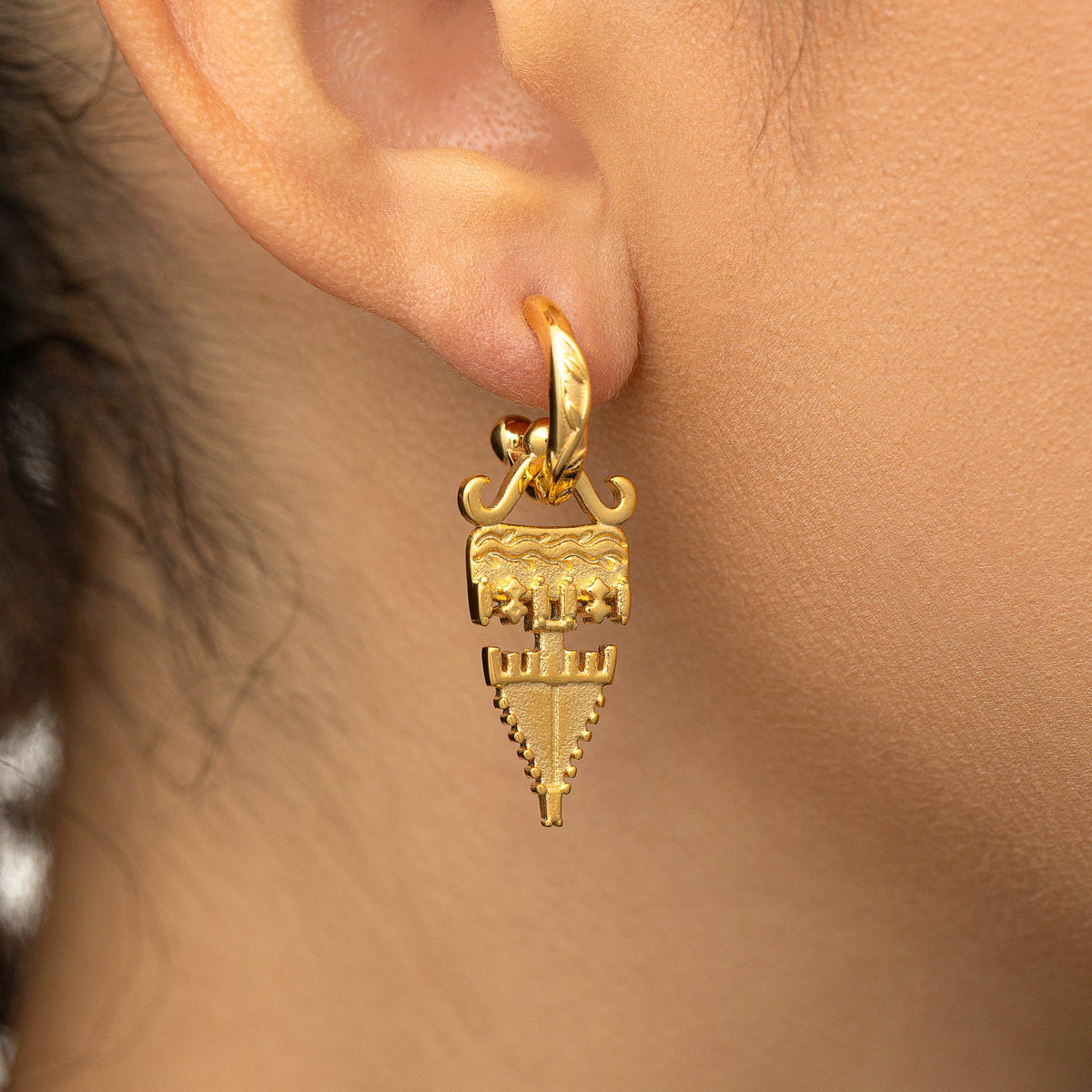Gold Tatreez Earring with a textured geometric drop worn on a woman's ear in a close-up shot.