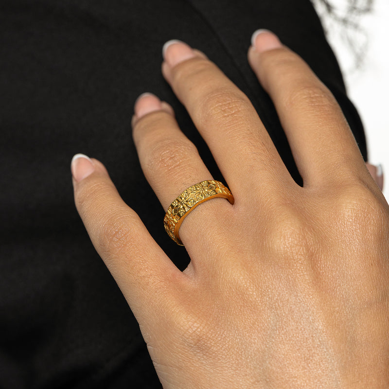 Woman wearing a gold Tatreez Ring with raised tatreez patterns on her finger in a close-up hand shot.