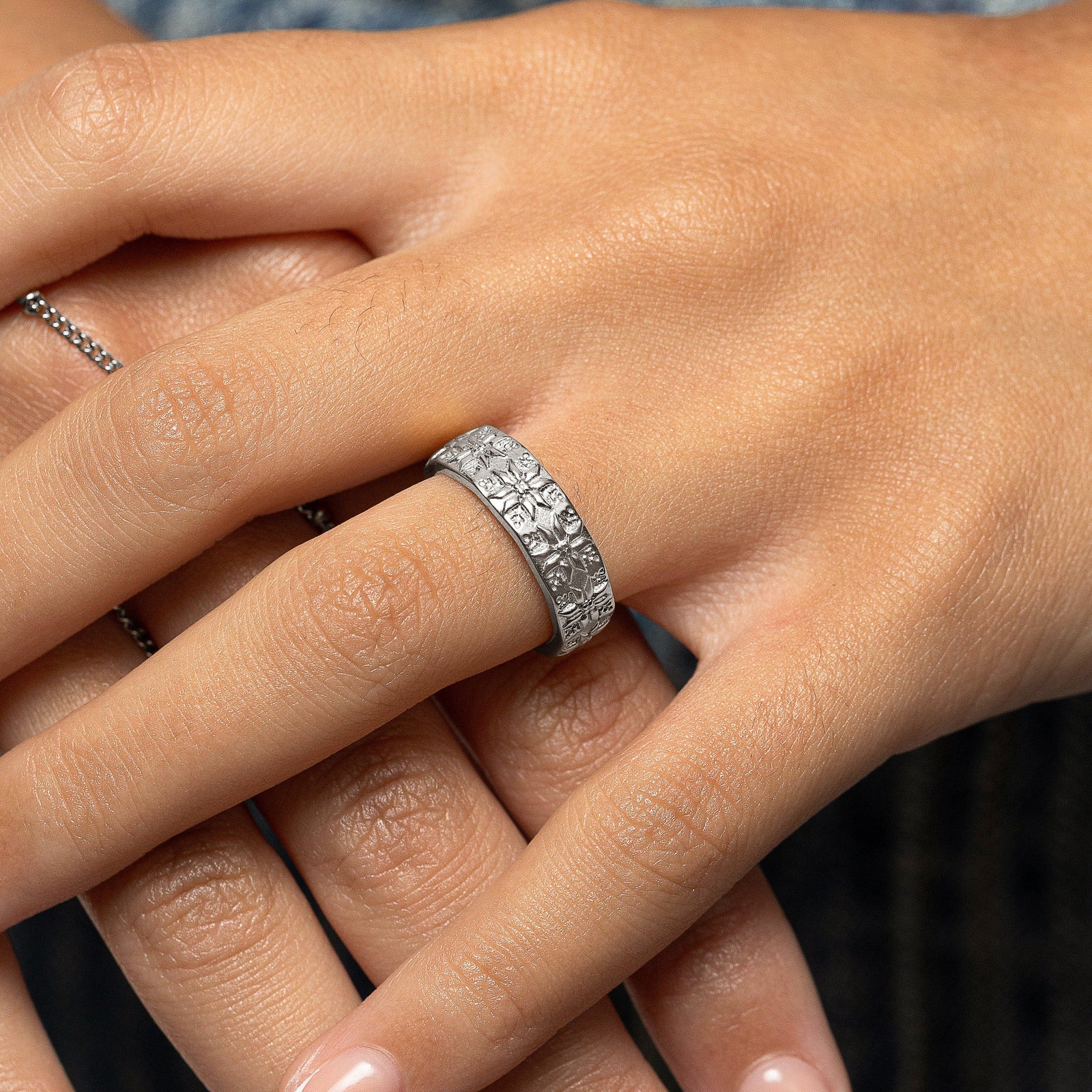 Woman wearing a silver Tatreez Ring with raised tatreez patterns on her finger in a close-up hand shot.