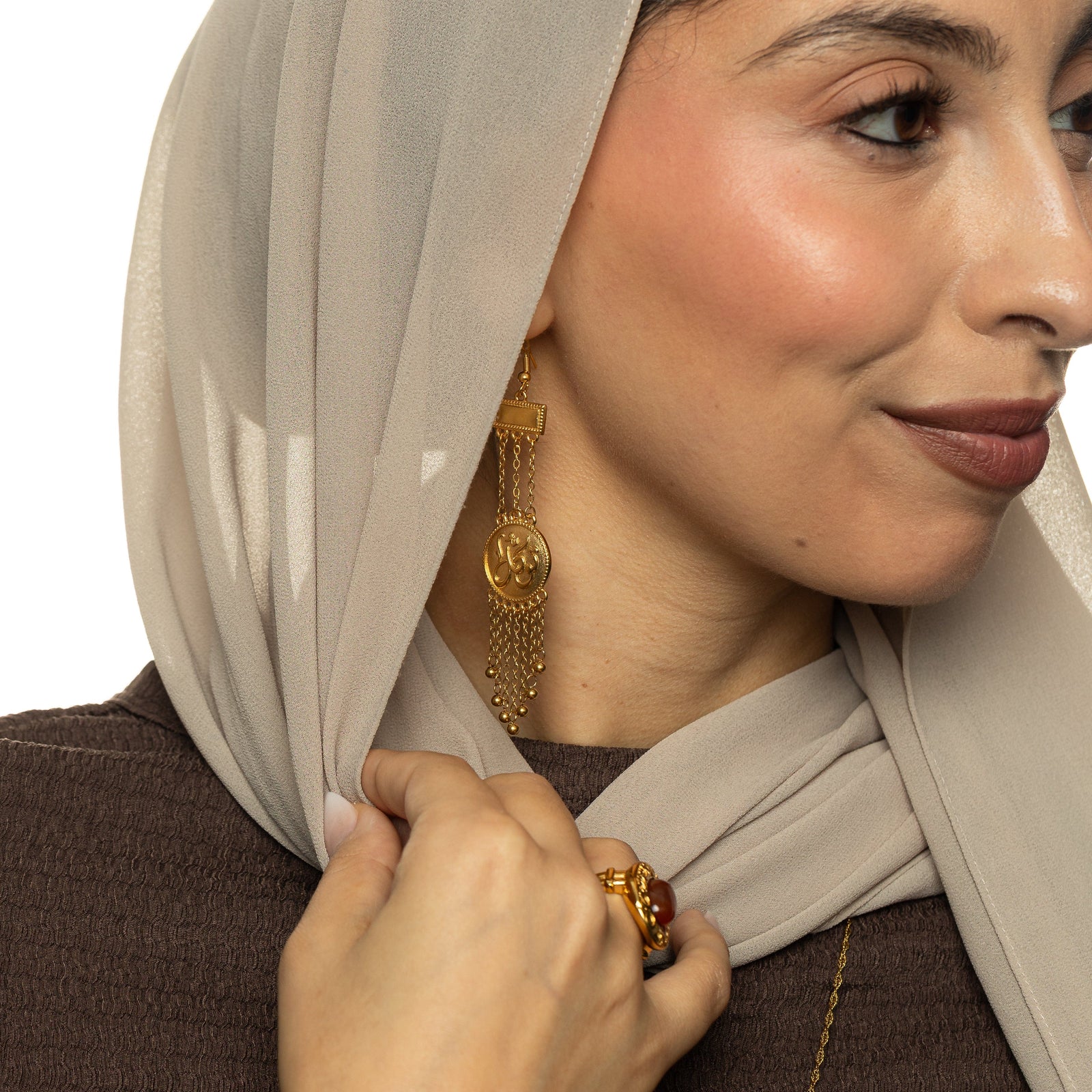 Gold Tawakkul | Trust Raining Earrings worn by a woman, featuring circular coin-style pendants engraved in Arabic calligraphy with multiple dangling gold chains and small bead drops.