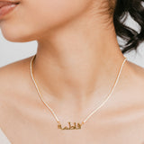 Model wearing 18k gold-plated Tennis Name Bracelet featuring a clear pavé crystal chain with a central custom Arabic calligraphy nameplate.