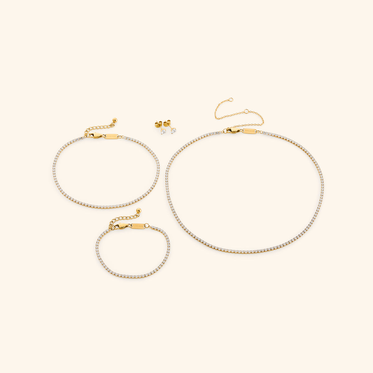 18k gold-plated Tennis Collection featuring the Tennis Necklace, Tennis Anklet, Tennis Bracelet, and Tennis Earrings.