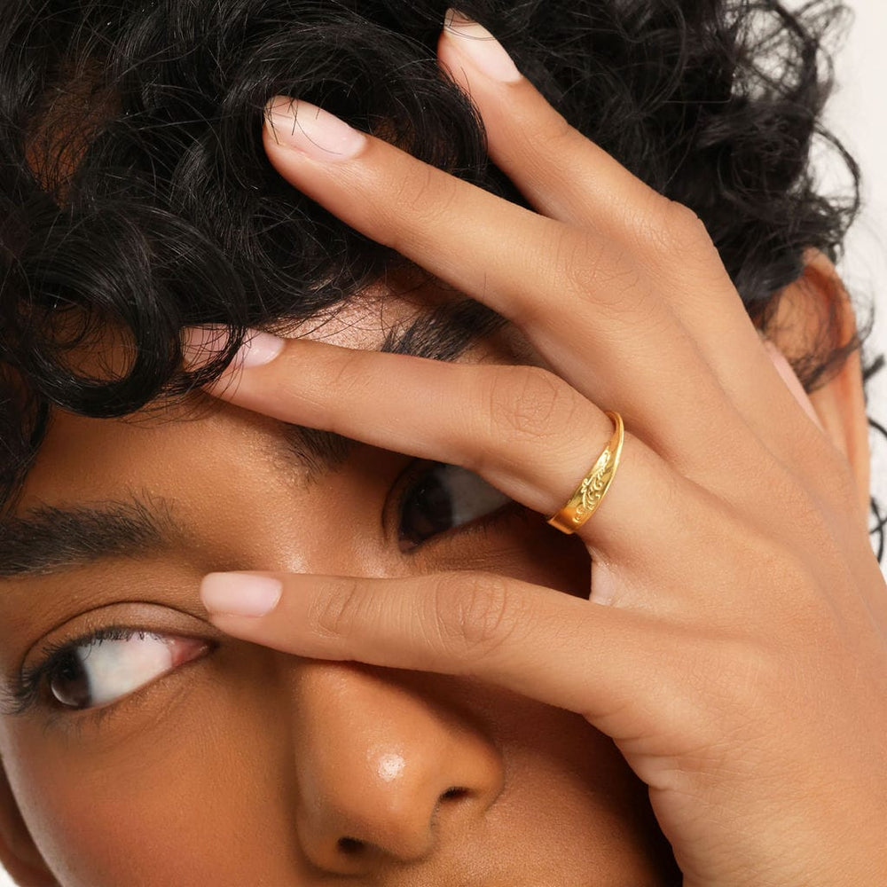 Close up of the model's left hand covering their face to show gold Tidal Wave Ring.