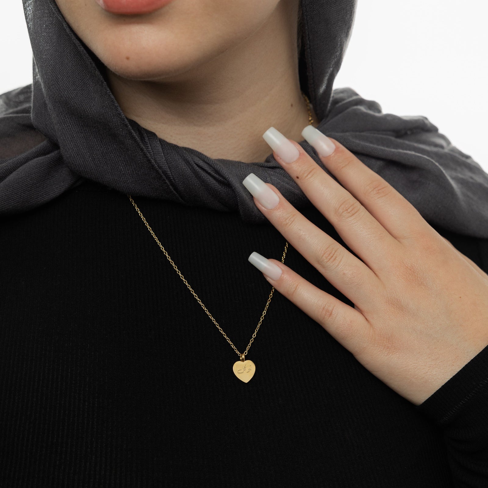 Close up of the gold Trust | توكل Charm Necklace as worn by the model.