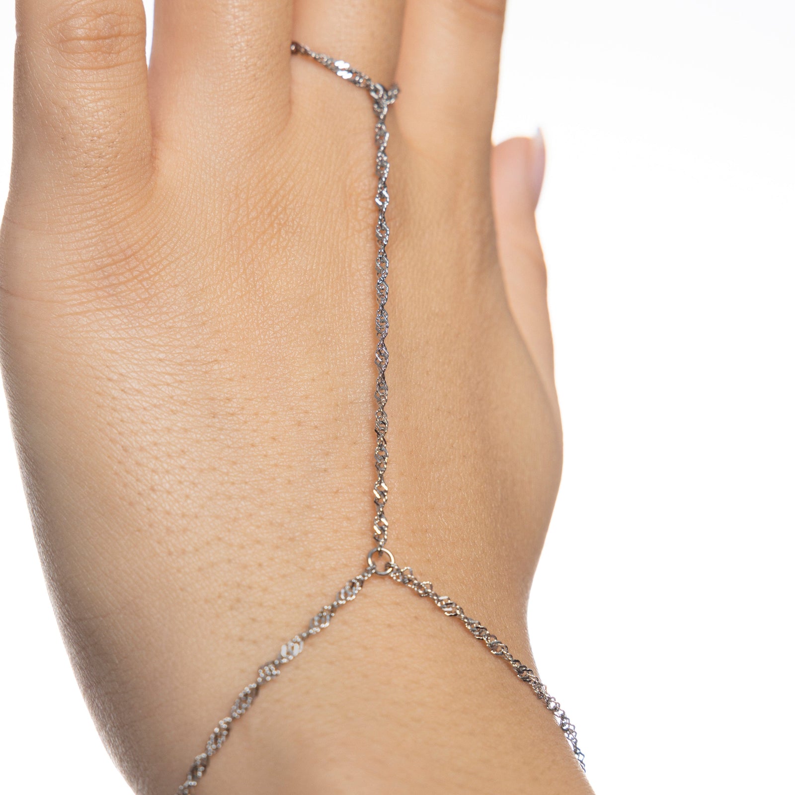 Zoomed-in detail of silver twisted hand chain connecting from wrist to middle finger, spiral texture of the chain clearly visible on skin.