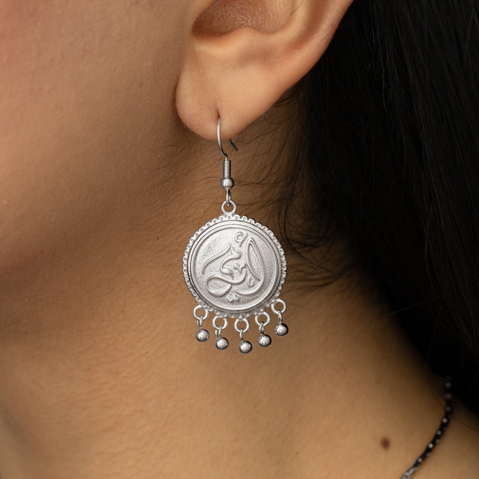 Close up photo of the silver Ummi | Mother Coin Earring as worn by the model.