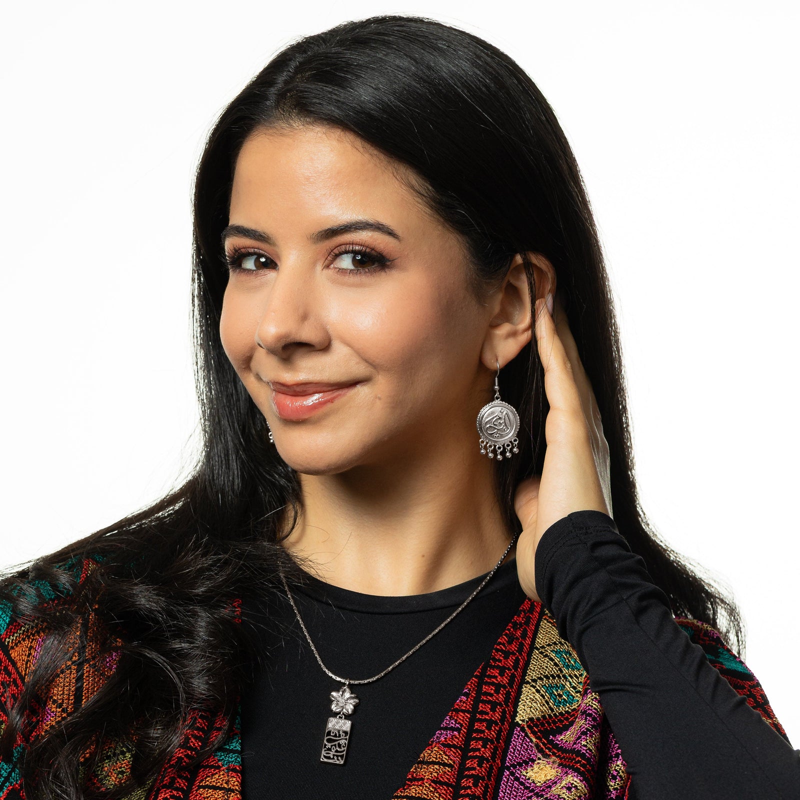 Model touching their hair and left ear as they show the silver Ummi | Mother Coin Earrings dangling from their left ear. Model is also wearing the silver Blooming In Our Hearts Necklace.