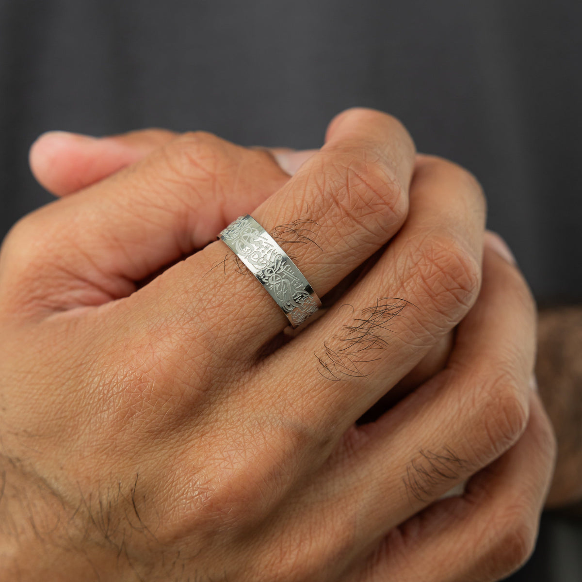 Close up of the silver "With Hardship Comes Ease" Ring V2 | Men as worn by the model on their right index finger.